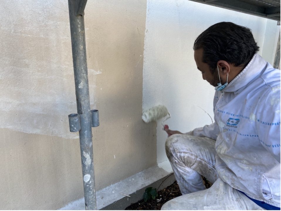 Homme en train de peindre un mur avec un rouleau. Trianon Façades.
