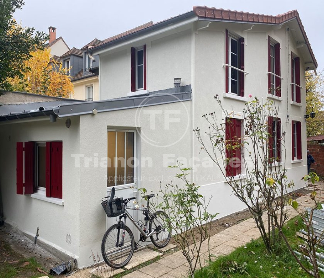 Maison blanche avec volets rouges, vélo devant.